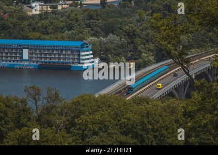 An einem warmen Sommertag in der Ukraine fährt eine neue U-Bahn in Kiew über die Brücke über den Fluss Dnjepr in Richtung Hydropark und Dnipro-Viertel. Stockfoto