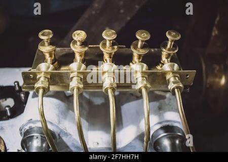 Rohre aus Metall oder Kupfer aus Messing mit Rückschlagventilen oben in einem alten Dampfboot. Rohrleitungen mit Ventilen einer alten Dampfmaschine. Stockfoto