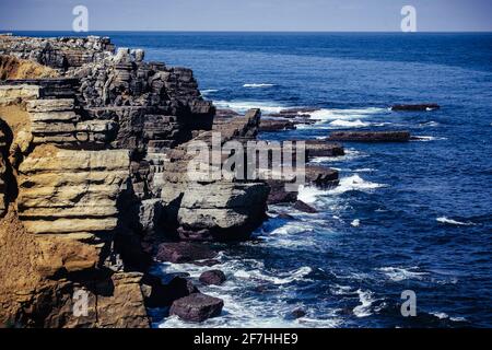 Felsformationen, die sich bis ins Meer rund um Peniche, Portugal, erstrecken. Küste bricht zusammen, Steine im Meer, an einem bewölkten Tag Stockfoto