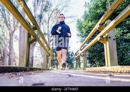 Junge Erwachsene Mann Sportprofi läuft durch einen Park in Frühlings- oder Sommertraining bei Sonnenuntergang Point Elite Sport Personal Kümmern Sie sich um das tägliche Training Stockfoto
