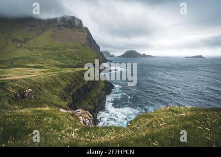 Färöer-Inseln mit stürmischer Sicht auf Tindholmur und Drangarnir auf der Insel Vagar vom Mulafossur-Wasserfall aus gesehen. Niedrige Wolken mit atlantik Stockfoto