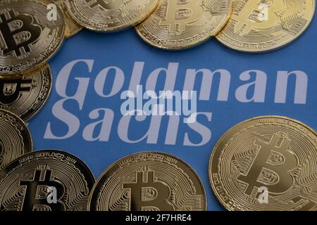Bitcoin-Münzen umgeben das verschwommene Goldman Sachs-Logo auf dem Papier. Konzept. Selektiver Fokus. Stafford, Großbritannien, 7. April 2021. Stockfoto