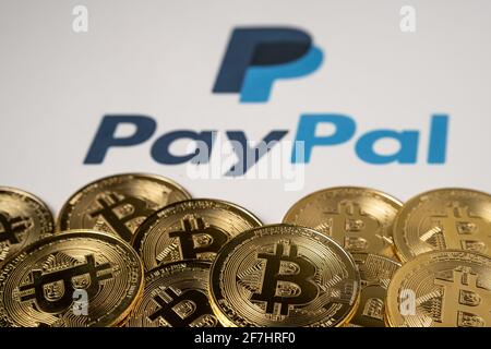 Bitcoin-Münzen auf der Vorderseite und verschwommenes PayPal-Logo auf dem bedruckten Papierhintergrund. Konzept. Selektiver Fokus. Stafford, Großbritannien, 7. April 2021. Stockfoto