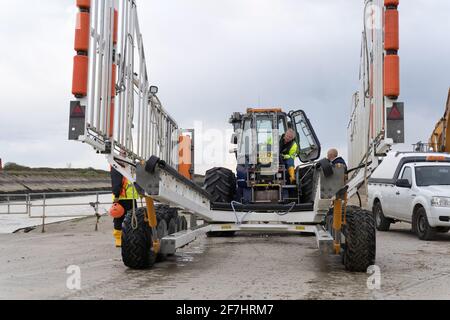 Betreiber des Strandtraktors TW56H vor der RNLI Rye Harbour Lifeboat Station, Rye, East Sussex, England Stockfoto