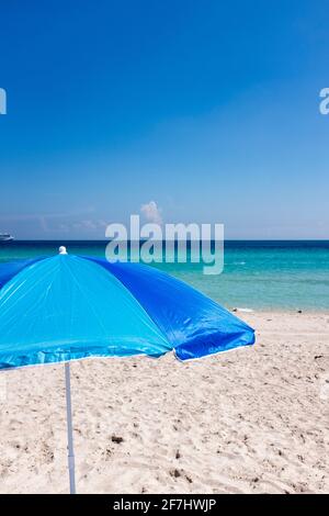 Ein blauer Sonnenschirm, eingerahmt vom azurblauen Wasser des Atlantiks vor South Beach, Miami Beach, Florida Stockfoto