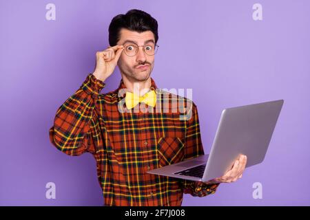 Foto eines jungen, ernsthaft nachdenklichen Mannes in einer Brille, der arbeitete In Laptop denken isoliert auf lila Hintergrund Stockfoto