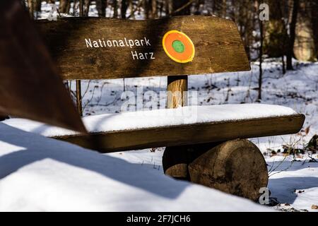 Bad Harzburg, Deutschland. April 2021. Schneereste liegen auf einer Bank mit der Aufschrift 'Nationalpark Harz'. Quelle: Swen Pförtner/dpa/Alamy Live News Stockfoto