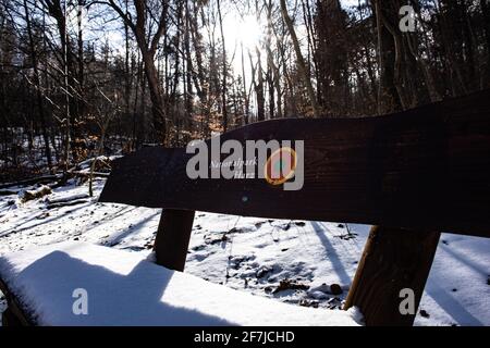 Bad Harzburg, Deutschland. April 2021. Schneereste liegen auf einer Bank mit der Aufschrift 'Nationalpark Harz'. Quelle: Swen Pförtner/dpa/Alamy Live News Stockfoto