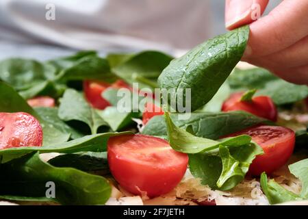 Pizza mit Käse, Tomaten, Spinat und Räucherwurst Stockfoto