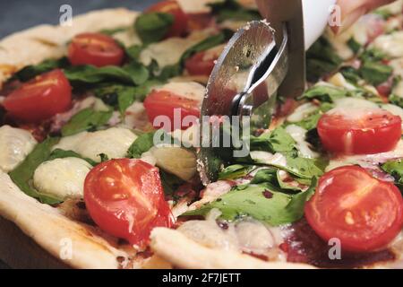 Pizza mit Käse, Tomaten, Spinat und Räucherwurst Stockfoto