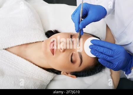 Reinigung Gesicht comedone Löffel. Schöne Frau bekommt Entfernung von Komedonen, Mitesser, Akne in einer Schönheitsklinik. Blick von oben Stockfoto