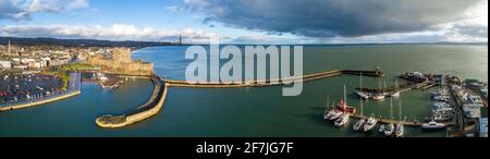 Breites Luftpanorama von Carrickfergus bei Belfast mit mittelalterlichem normannischem Schloss, Hafen, Yachthafen, Yachten, Wellenbrecher, Bootsrampe, Belfast Laugh, Parkplatz Stockfoto