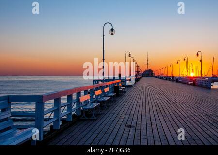 Sonnenaufgang am hölzernen Pier namens Molo in Sopot, Polen mit Sonneneinstrahlung auf Bänken Stockfoto