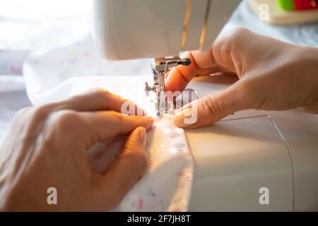 Junge Frau näht Kleidung auf der Nähmaschine. Nahaufnahme Stockfoto