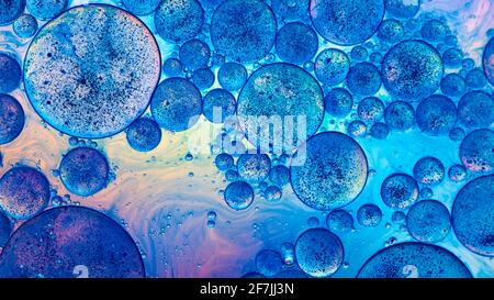 Makro der Öltropfen und Pigment auf Wasseroberfläche mit hellem Hintergrund Stockfoto