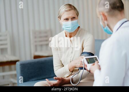 Hausarzt, der den Druck einer reifen Frau misst. Stockfoto