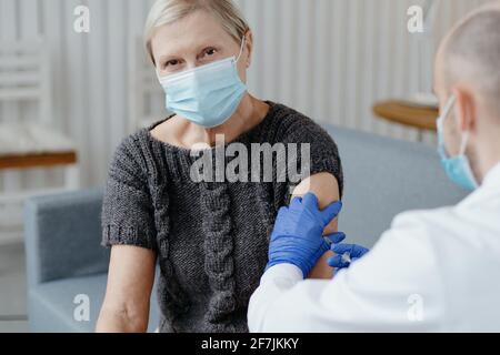 Erfahrener Arzt, der eine reife Frau impft. Konzept der Impfung. Stockfoto