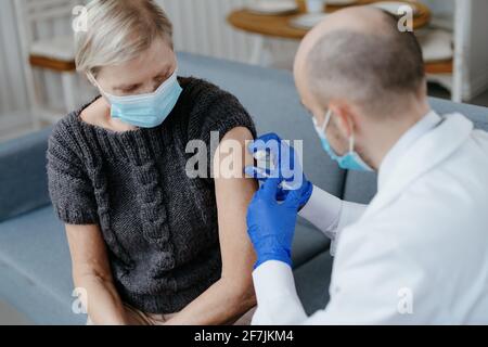 Erfahrener Arzt, der eine reife Frau impft. Konzept der Impfung. Stockfoto