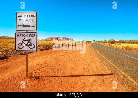 Tierschutz und Fahrradwarnschild in Northern Territory, Red Centre, Zentralaustralien. Ayers Rock im Uluru-Kata Tjuta National Park Stockfoto