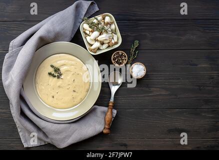 Teller mit köstlicher Pilzsahnesuppe mit Thymian auf dem Holztisch. Horizontale Draufsicht von oben, Kopierbereich Stockfoto