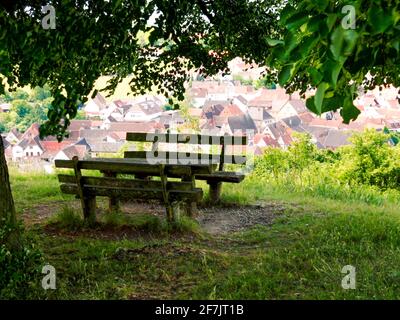 Ruhebereich Bank unter Bäumen Vordach der Blätter über a Dorf Blick auf die Dächer des Dorfes roten Ziegel Blick Pause Stop über Wanderweg Pilger Stockfoto