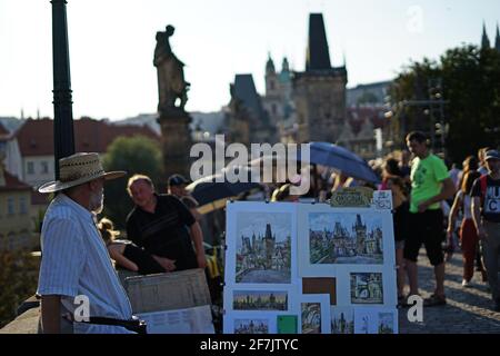 Prag, Tschechische Republik - 23 2019. August: Abendliche Atmosphäre auf der Karlsbrücke mit einem Mann, der Gemälde verkauft Stockfoto