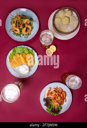 Snacks und Bier Draufsicht. Fotos von Lebensmitteln auf burgunderrotem Hintergrund. Stockfoto