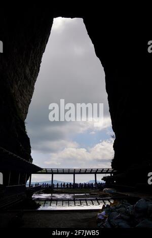 Ein riesiges, von der Natur geformtes Loch namens TianMenDong (auch bekannt als Sky Hole) im Zhangjiajie National Forest Park, durch das ein wolkiger Himmel blicken kann. Stockfoto