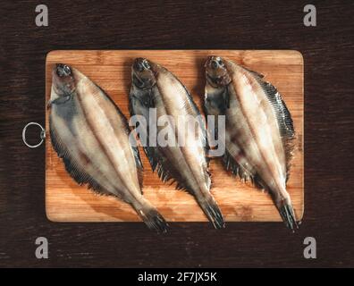 Roher Flunder Fisch, Meeresfrüchte auf einem hölzernen Schneidbrett . Gesunde Ernährung Konzept. Draufsicht Stockfoto