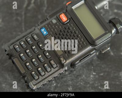 Kompaktes, aber leistungsstarkes Walkie-Talkie in Schwarz mit Display auf dunklem Hintergrund. Nahaufnahme Stockfoto