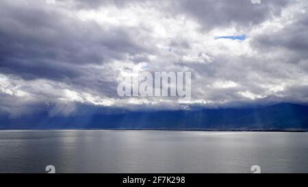 Sonnenlicht, das durch den wolkigen Himmel auf dem Seewasser scheint. Stockfoto