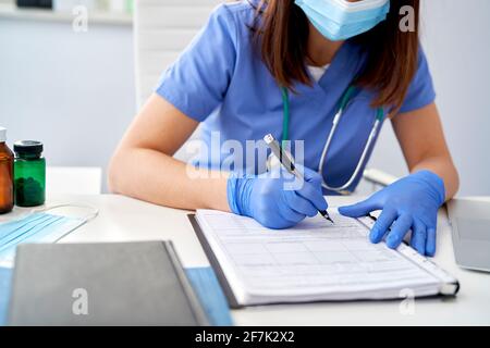 Nahaufnahme einer Ärztin, die Krankenakten ausfüllt Stockfoto