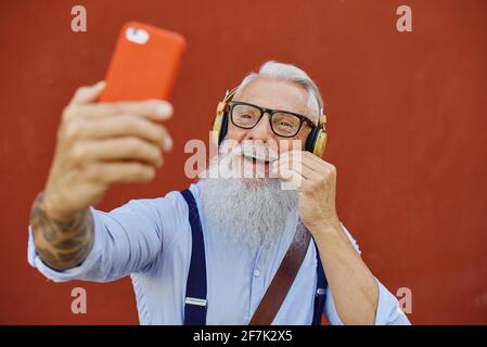 Senior Hiphster man erstellt mit der Smartphone-App Playlist mit Musik - Trendiger Tattoo-Typ, der Spaß mit der Mobiltelefontechnologie hat - Tech und Joyful Stockfoto