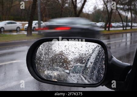 Blick vom Rückspiegel an einem regnerischen Tag mit Wasser Tropfen Stockfoto