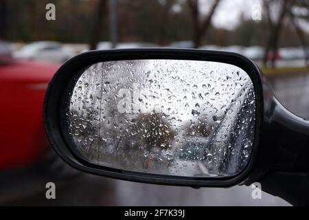 Blick vom Rückspiegel an einem regnerischen Tag mit Wasser Tropfen Stockfoto