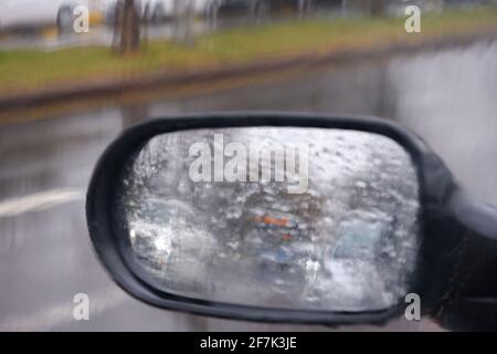 Blick vom Rückspiegel an einem regnerischen Tag mit Wasser Tropfen Stockfoto