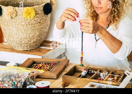 Frau zu Hause machen handgemachten Schmuck. Box mit Perlen auf alten Holztisch. Ansicht mit Frau Hände - Tutorial zu lernen, wie man Armbänder und Schmuck zu machen Stockfoto