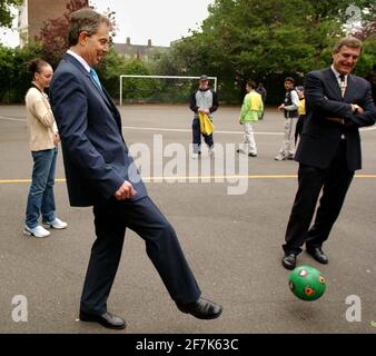 Der britische Premierminister Tony Blair (Mitte) und der ehemalige West Ham- und England-Star Trevor Brooking spielen am Donnerstag, 9. 2002, mit einheimischen Kindern in den Newington Gardens in London Fußball. Blair startete ein neues Regierungsprogramm, um junge Menschen von der Straßenkriminalität abzubringen Stockfoto