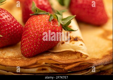 Frische rote Erdbeeren und traditionelle russische Pfannkuchen. Woche der Fastnacht. Nahaufnahme, selektiver Fokus. Stockfoto