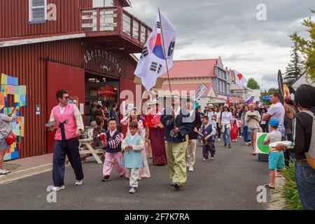 Menschen in koreanischem Volkstracht, die eine südkoreanische Flagge tragen, nehmen an einer multikulturellen Parade Teil. Tauranga, Neuseeland Stockfoto