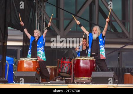 Trommler spielen Taiko oder traditionelle japanische Holztrommeln. Sie tragen Happi (japanisch gemusterter Mantel) Stockfoto