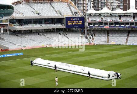 Die Bodenmitarbeiter bringen die Abdeckungen aufgrund von Regen während des LV= Insurance County Championship-Spiels auf dem Lord's Cricket Ground, London, heraus. Bilddatum: Donnerstag, 8. April 2021. Stockfoto