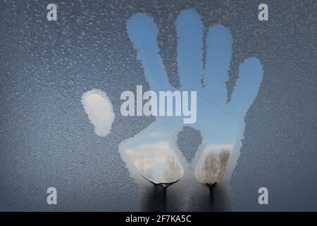 Spuren der Handflächen auf dem mit Frost bedeckten Glas. Stockfoto