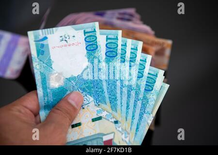 Herrenhände halten und zählen die katarischen Banknoten. 100 Neue Noten für Rial. Business- und Finanzkonzept Stockfoto