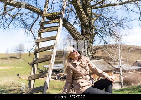 Eine junge Frau saß an einem Baumstamm in einem Angezeigt Stockfoto