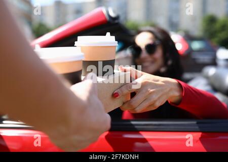 Der Kellner servierte der Frau Kaffee in der Nahaufnahme des Autos. Coffee to go-Konzept Stockfoto