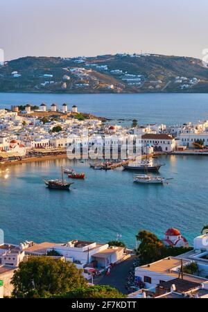 Wunderschöne Sonnenuntergangsansicht von Mykonos, Kykladen, Griechenland, seinem Hafen, Windmühlen. Kreuzfahrten, Schiffe, weiß getünchte Häuser. Urlaub, Freizeit, mediterraner Lebensstil Stockfoto