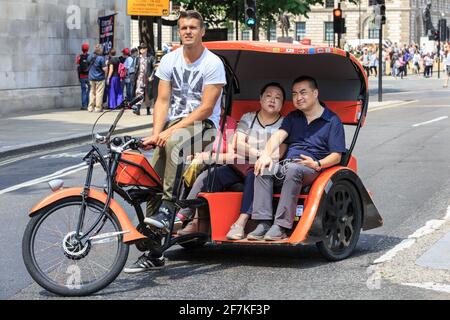 Asiatische Touristen auf einer Fahrrad-Rikscha (Fahrrad-Taxi oder Pediküre) in Westminster, London, England Stockfoto