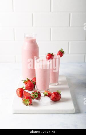 Frischer hausgemachter kalter Erdbeer-Smoothie mit Eiswürfeln und frischen Erdbeeren auf weißem Hintergrund. Stockfoto