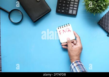 Handzeichnung Text FAQ auf Notizblock auf blauem Hintergrund Stockfoto